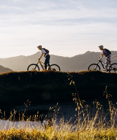 Zwei Personen am E-Mountainbike am Berg bei Sonnenuntergang | © saalbach.com, Karin Pasterer