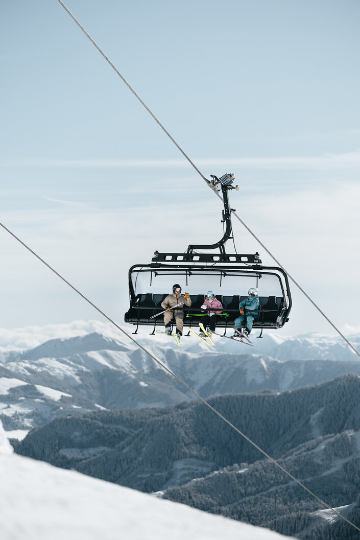Skicircus Saalbach Hinterglemm Leogang Fieberbrunn drei Personen fahren den Skilift hinauf | © saalbach.com, Georg Lindacher