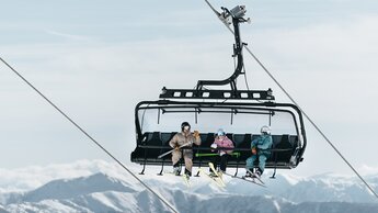 Skicircus Saalbach Hinterglemm Leogang Fieberbrunn drei Personen fahren den Skilift hinauf | © saalbach.com, Georg Lindacher